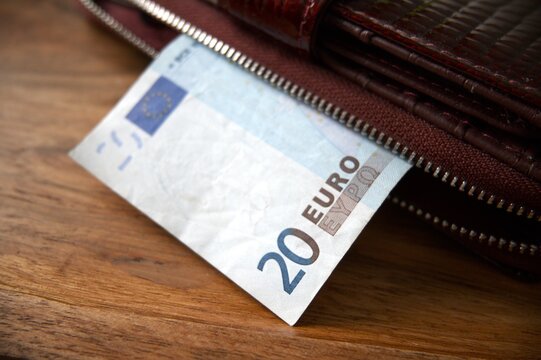 A twenty euro banknote partly visible next to a women&rsquo;s wallet, close up detail.