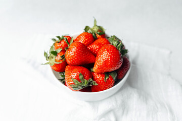 Fresh strawberries piled in a bowl on a soft cloth background