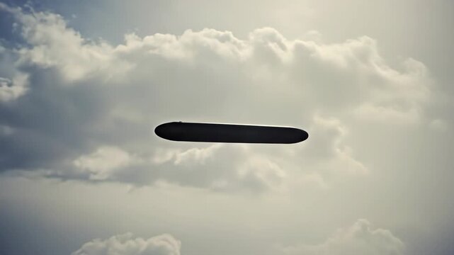 Dark silhouette of blimp flying through cloudy sky. Airship or zeppelin traveling over the clouds in daylight. Futuristic aviation footage.