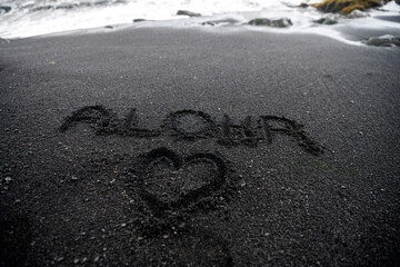 Word "Aloha" with a heart drawn in black sand at Black Sand Beach, Big Island, Hawaii. © Gary
