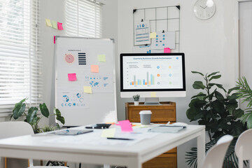 Fototapeta premium Modern office workspace with chart presentation, sticky notes and computer screen showing business growth report, bright natural light and calm