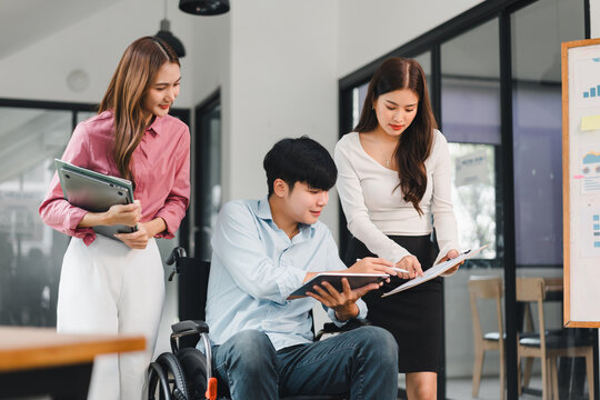 Young man in wheelchair collaborating with colleagues disability inclusion teamwork office meeting smiling professional