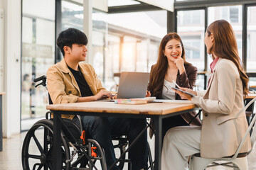 Young man in wheelchair meeting colleagues around table disability inclusive teamwork smiling professional office