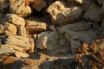 Rough stone wall texture. Close-up view of natural rocks with orange, grey, and brown tones. Perfect for architectural backgrounds, 3D modeling, or design templates.