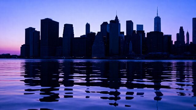 City skyline at dusk reflected in calm water - Powered by Adobe