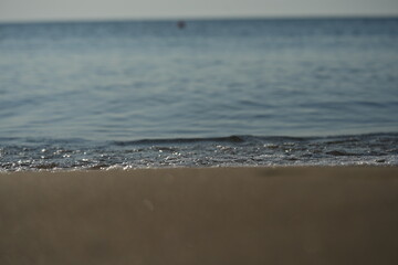 Blurred view of a beach and sea waves. Soft focus abstract background with sand and ocean horizon. Perfect for travel, vacation, summer, or minimalist design themes