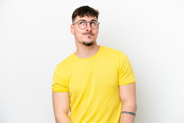 Obraz premium Young caucasian handsome man isolated on white background having doubts while looking up