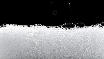 Close-up of white frothy bubbles against a solid black background, creating a contrast of textures and tones