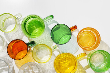 Colored Glasses pattern with shadow and sunlight reflection white background, minimal aesthetic top view summer still life, refraction at shine drink, caustic effect, green yellow glass cups