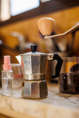 Ingredients for making coffee. Moka pot, bean spray, coffee grinder with coffee beans standing on the kitchen table.
