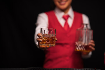 Bartender woman pours whiskey into a glass in a restaurant.	