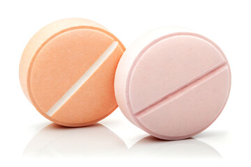 Two round peach and pink pills with a white score line on a white background