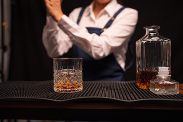 Bartender woman pours whiskey into a glass in a restaurant.	