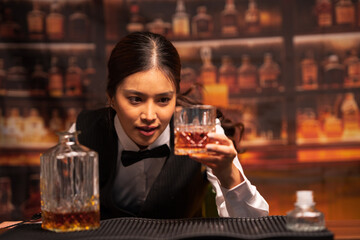 Bartender woman pours whiskey into a glass in a restaurant.	