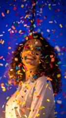 Joyful woman laughing under vibrant falling confetti, celebrating a moment of pure happiness and success