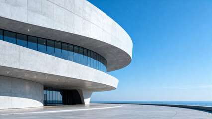 Fototapeta premium Modern curved architectural structure with glass windows and concrete facade under clear blue sky