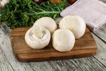 White champignon mushrooms heap over board