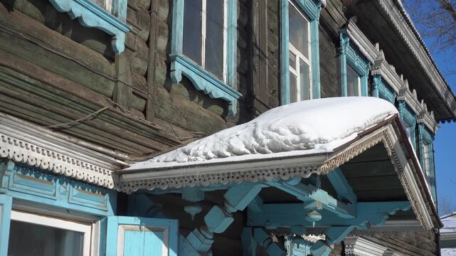 Gimbal close-up shot of ancient wooden Slavic house. Detailed view of log cabin, carved shutters, windows, Traditional wooden architecture. Winter sunny snowy day