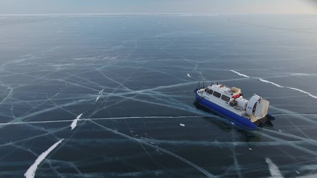 Aerial abstract hovercraft speeding across vast cracked ice of frozen lake. Fast vehicle movement, endless icy expanse, horizon. Northern winter expedition travel concept, abstract natural landscape