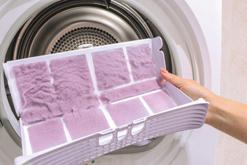 close up female hand taking lint out from dirty air filter of dryer machine after drying. cleaning...