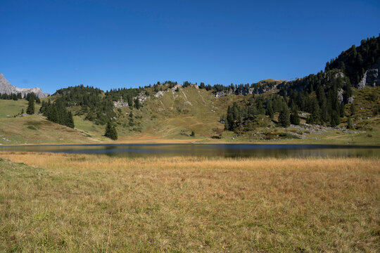 deep blue lake K&ouml;rbersee in the mountains of Vorarlberg in Warth Schr&ouml;cken with reflection of the alpine landscape 