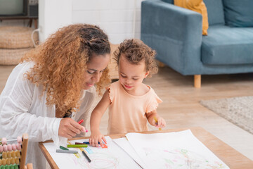 Enjoy happy smiling love family. Mother with little girl learning and writing in book with pencil making homework at home. Education concept	