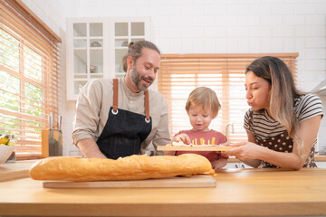 Beautiful cute family having fun while cooking together in the kitchen at home. Family with child in kitchen having breakfast.	