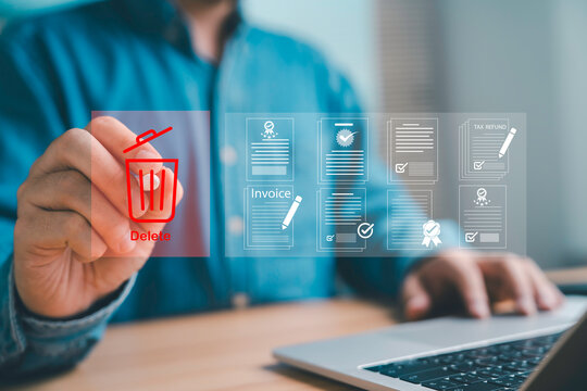 Businessman using digital interface to delete electronic documents invoices and tax forms on laptop Concept of data management paperless office and secure file storage