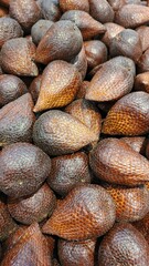 Close up of a pile of snake fruit being sold at the market in the background.	

