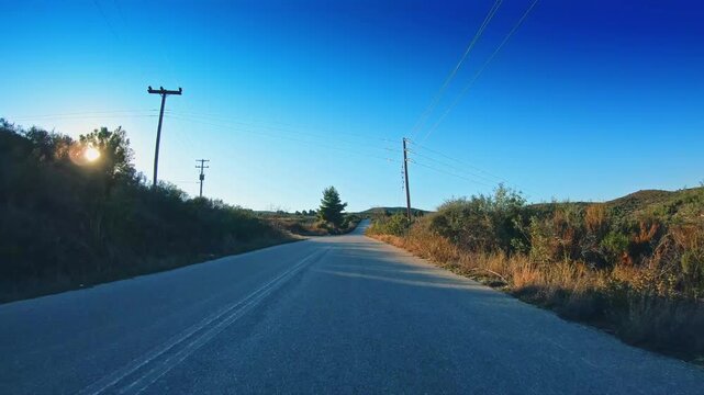 POV drive car travel, countryside vacant road, gleaming sun blue sky horizon