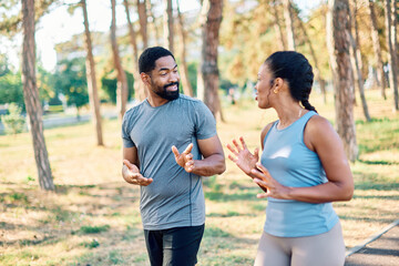 Smiling active mature mid aged couple jogging exercising and having fun and laughing together taking a break in the park