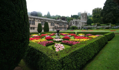 Garden with neatly trimmed hedges and arranged flowers in yard of Lanhydrock House, traditional...