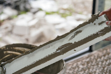 Installing foam board insulation in new house, closeup detail to polystyrene board with wet cement mix