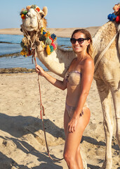 Young woman posing next to camel at Egypt beach