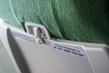 Life vest under your seat text, with Amharic (Ethiopian language) translation above, on an passenger airplane chair