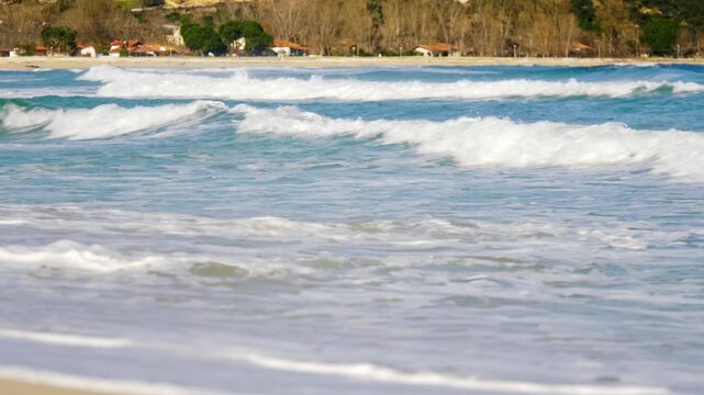 Mediterranean bay in winter, waves washing ashore, sandy beach with blue waters