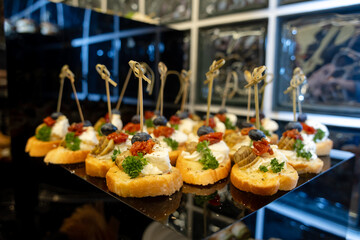 Canapes with Cheese and Olives at Banquet. Served on a black glossy tray at a buffet or event.