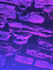 Purple illuminated brick wall texture at night