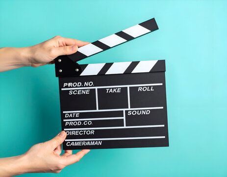 Film clapperboard held by hands on blue background, symbolizing filmmaking and cinema production.