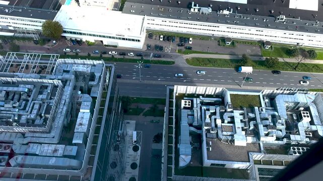 Ventilation systems and pipes on the roofs of buildings. View from above. Cars passing by.
