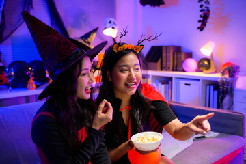 Friends wearing Halloween costumes watching movie enjoying popcorn during a fun spooky party at home