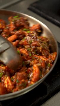 Baby corn manchurian being tossed in a pan