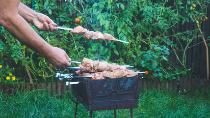 Shashlik on skewers is being cooked on charcoal in a barbecue close-up.