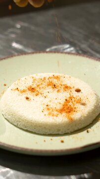 Karam being sprinkled on a fresly Thatte idly