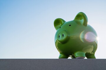 Bright green ceramic piggy bank against blue sky savings finance money investment concept.