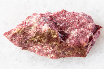 sample of raw thulite mineral on white marble
