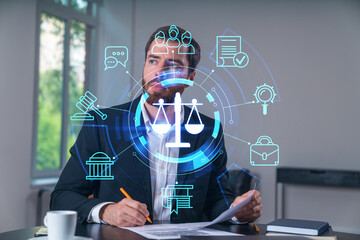 Thoughtful man working at desk with justice scale icons overlayed digitally.