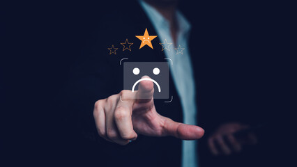 Business person touching a virtual sad face and one star rating on black background, showing poor customer satisfaction, negative review, complaint feedback, and brand risk in product or service