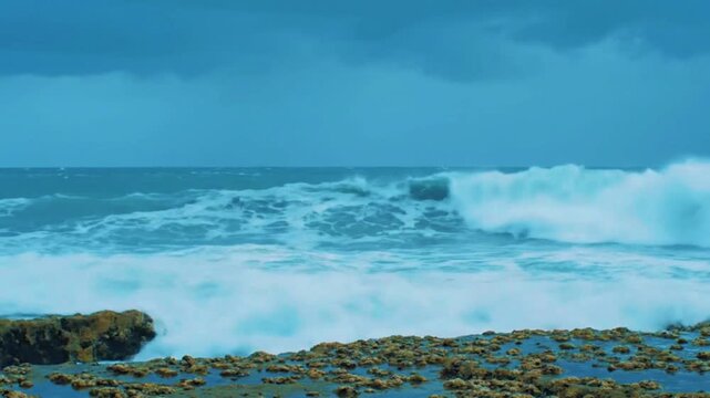 A realistic 4K cinematic turbulent wave in storm approach, choppy blue-green water rolling in pulsing motion, spray heavy at crest, under cool diffused pre-storm light, sky blue-gray with cloud build