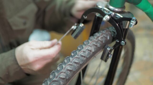 Workshop. A worker uses a wrench to install rim brakes on the front fork of an old bicycle.